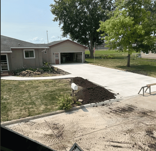 Newly paved driveway with landscaping work and fresh dirt in a residential yard.