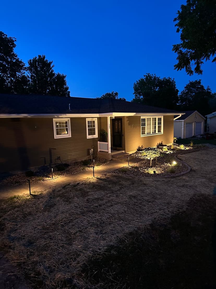 Beautifully illuminated home at dusk with garden landscaping and pathway lighting.