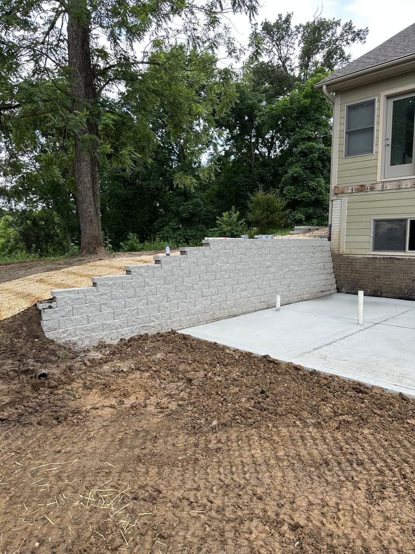 Retaining wall built beside house, surrounded by dirt and landscaping in progress.